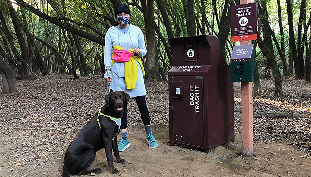 woman and dog next to dog waste station 